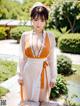 A woman in a white and orange kimono posing for a picture.