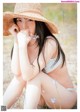 A woman in a straw hat sitting in a field of flowers.