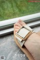 A woman's hand holding a pair of sandals on a window sill.