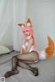 A woman in a fox costume sitting on a bed.