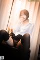 A woman in a white shirt and black stockings sitting on a chair.