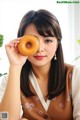 A woman holding a donut in front of her face.