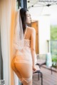 A woman in a white lingerie leaning against a window.