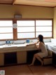 A woman sitting on a bench in a bathroom next to two sinks.