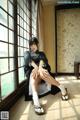 A woman sitting on the floor in front of a window.